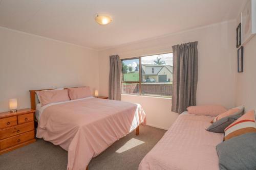 a bedroom with two beds and a window at Hosts on the Coast Cosy on Cath in Whitianga