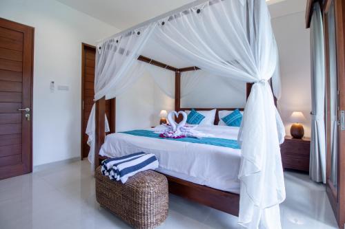 a bedroom with a canopy bed with a ottoman in a room at Sayang Sanur Duplex in Sanur