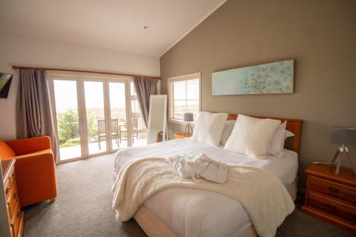 a bedroom with a large white bed and a balcony at Pakiri Beach Holiday Park in Pakiri