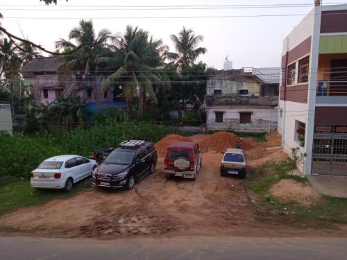 three cars parked in a dirt lot next to a building at Paradise corner in Pondicherry