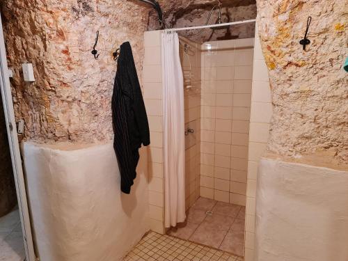 a shower stall with a black jacket hanging on a wall at Underwood Court fresh Dugout- Hosted by Coober Pedy Accommodations in Coober Pedy