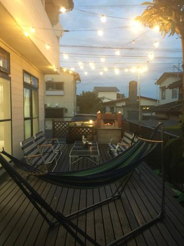 a hammock on a deck with chairs on a house at Guesthouse Oyado Iizaka in Fukushima