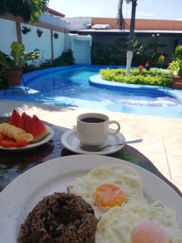 a plate of eggs and fruit and a cup of coffee at Berlor Airport Inn in Alajuela City