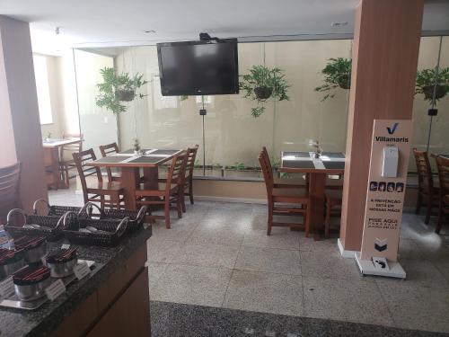 a restaurant with tables and chairs and a tv on the wall at Villa Park Hotel Fortaleza in Fortaleza