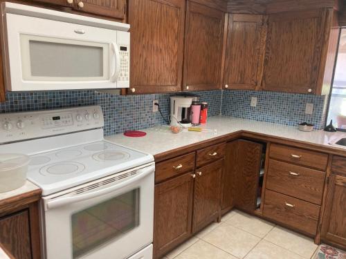 una cocina con electrodomésticos blancos y armarios de madera en Irises House - private room in home, en Kissimmee