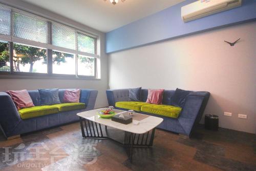 a living room with two blue couches and a coffee table at 樂客2館 in Hsia-shih