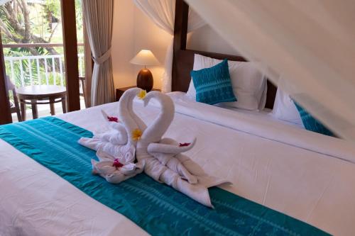 two swans made out of towels sitting on a bed at Sayang Sanur Duplex in Sanur