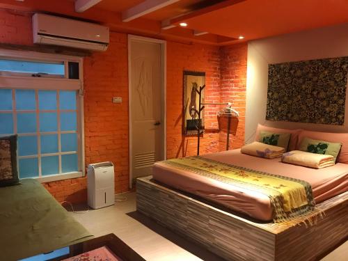 a bedroom with a large bed and a brick wall at A-HOME in Jiufen
