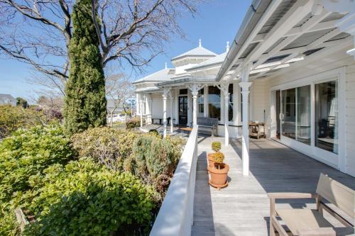 a porch of a white house with a bench at The Verandah - Napier Holiday Home in Onekawa