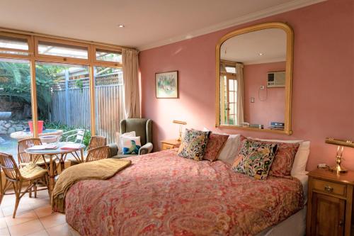 a bedroom with a bed with a mirror and a table at North Adelaide Heritage Cottages & Apartments in Adelaide