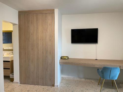 a room with a tv on the wall and a blue chair at Vistalmar Ocean Suites in Oranjestad