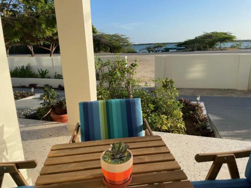 a wooden table and a chair with a cactus on a patio at Vistalmar Ocean Suites in Oranjestad