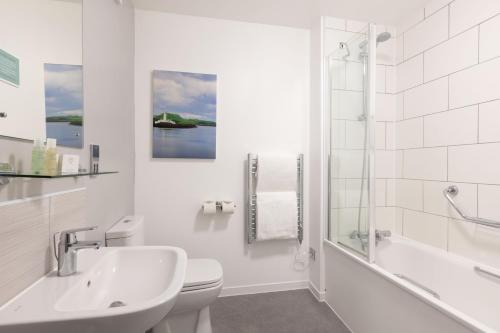 Baño blanco con aseo y ducha en The Great Western Hotel en Oban