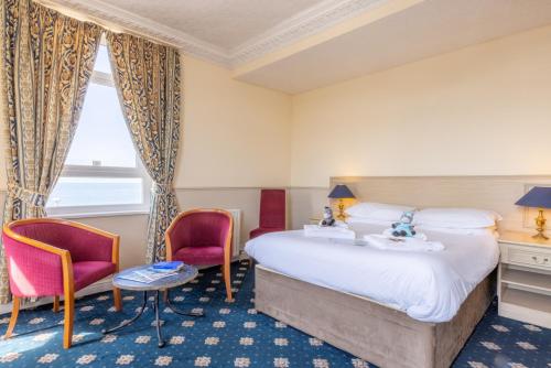 a hotel room with a bed and two chairs at The Caledonian Tower Hotel in Blackpool