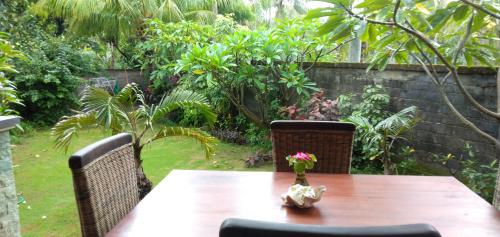 a wooden table with two chairs and a vase with flowers on it at Gede's Homestay in Tejakula