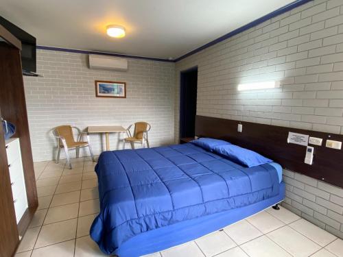 a bedroom with a blue bed and a table at Grand Hotel Motel in Clermont