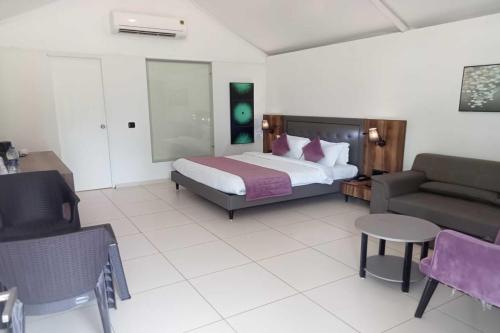 a bedroom with a bed and a couch and a chair at White Feather Resort Kauncha in Silvassa