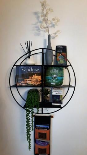 a glass shelf with books and a vase on a wall at La Maison du Chemin des Prairies in Morières-lès-Avignon