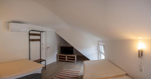a room with two beds and a staircase with a tv at Lauers Ferienwohnung 2 in Schoneck