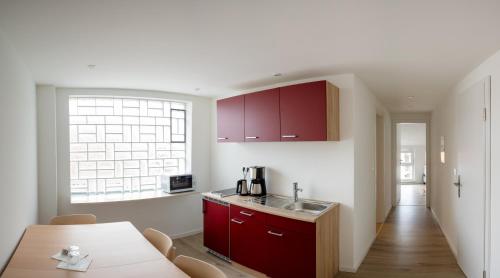a kitchen with red cabinets and a table and a window at Lauers Ferienwohnung 2 in Schoneck