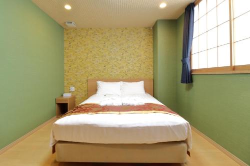 Arakawa-ku - Hotel / Vacation STAY 21942 في طوكيو: غرفة نوم بها سرير وبجدران خضراء ونافذة