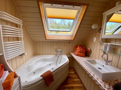 baño con bañera, lavabo y ventana en Die Adlerhütte, en Kurort Oberwiesenthal