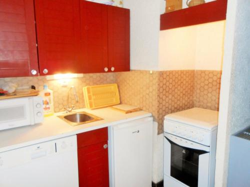 a small kitchen with white appliances and red cabinets at Studio Les Deux Alpes, 1 pièce, 4 personnes - FR-1-516-55 in Les Deux Alpes