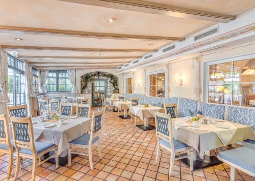 un restaurant avec des tables blanches et des chaises bleues dans l'établissement Gasthof Schorn, à Sankt Leonhard