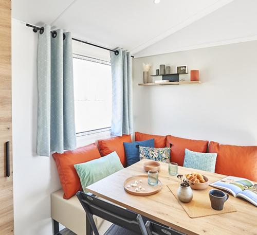- une salle à manger avec une table et un canapé orange dans l'établissement Camping de la Bonnette, à Caylus