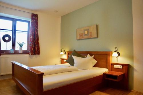 a bedroom with a bed with white sheets and a window at Pension Kramerhof in Taufkirchen