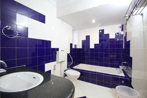 ein blau-weißes Bad mit einer Badewanne und einem WC in der Unterkunft Hotel Grand Arjun in Raipur