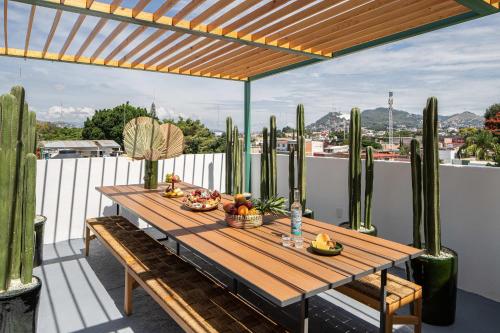 - une table en bois avec des fruits sur un balcon avec des cactus dans l'établissement HOLT - Villa Noria - La Casa del Barro Verde, à Oaxaca