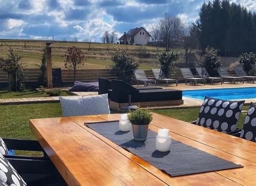 uma mesa de madeira com cadeiras e uma piscina em Zoe Luxury House em Gomirje