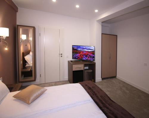 a bedroom with a bed and a flat screen tv at The Butterfly in Sîngeorgiu de Mureş