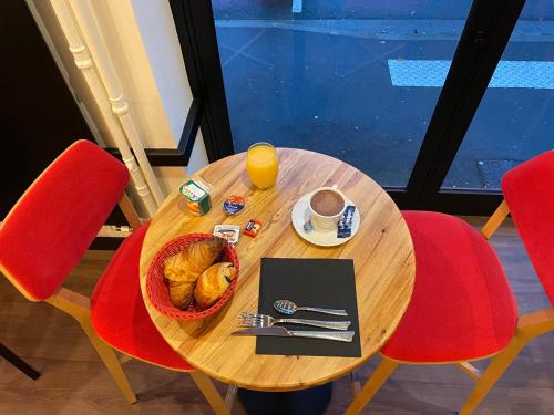 a table with a basket of bread and a cup of orange juice at Le Sporting in Le Mans
