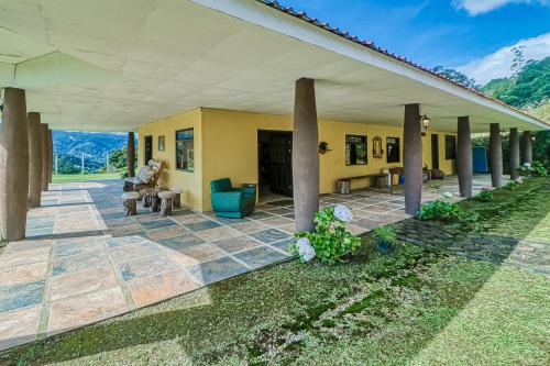 an outdoor patio of a yellow house with columns at Casita El Sastre in Paso Macho