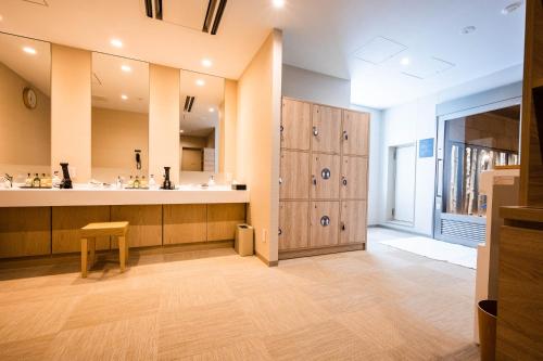 松本Tabino Hotel lit Matsumoto Milky white Onsen的大房间设有带柜台的大浴室