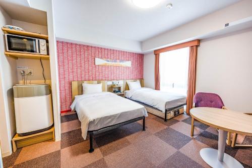松本Tabino Hotel lit Matsumoto Milky white Onsen的有两张床和一张桌子的酒店房间