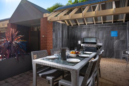 a table and chairs on a patio with a grill at MainStay Suites Kew in Melbourne
