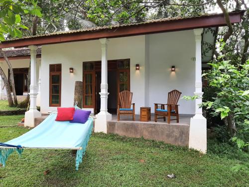 a bed in front of a house with two chairs at Jackland Holiday Cabanas in Demanhandiya