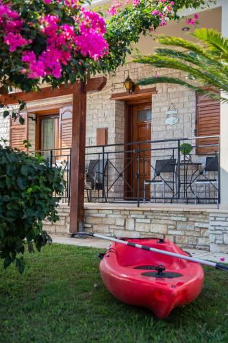 a red boat sitting on the grass in front of a house at Amaryllis Holiday Home in Agios Spiridon Fokidas