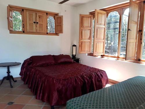 a bedroom with a bed and a table and windows at Refugio Villa Emilio in Villa de Leyva