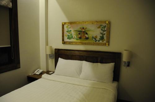 a bedroom with a bed and a picture on the wall at Hotel Veneto De Vigan in Vigan