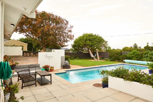 a backyard with a swimming pool with a table and chairs at 18 Abbotsford in Cape Town