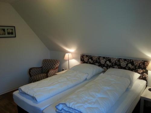 Cette chambre comprend un grand lit et une chaise. dans l'établissement Ferienhaus Emstal in Oberlangen, à Lathen