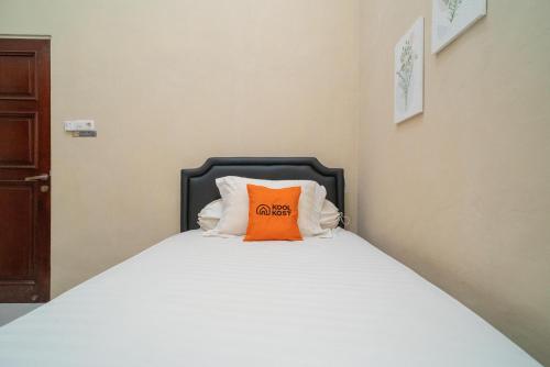 a bed with an orange pillow on top of it at Koolkost Syariah near Jalan Ahmad Yani Banjarmasin in Sungai Lutus