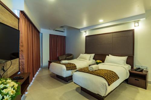 a hotel room with two beds and a flat screen tv at Arctic Hotel in Cochin