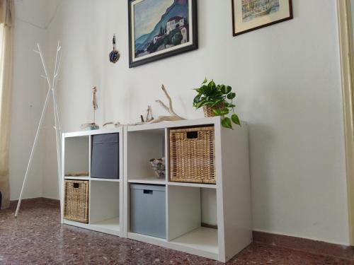 a white book shelf against a wall with a plant on it at Matina's agora apartment with Terrace in Leonidion