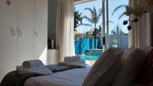 a bedroom with towels on a bed in front of a pool at Orchard Guesthouse in Bloemfontein