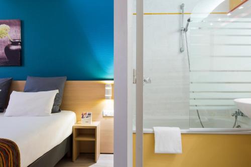 a bedroom with a bed and a shower and a sink at Comfort Hotel Montlucon in Montluçon